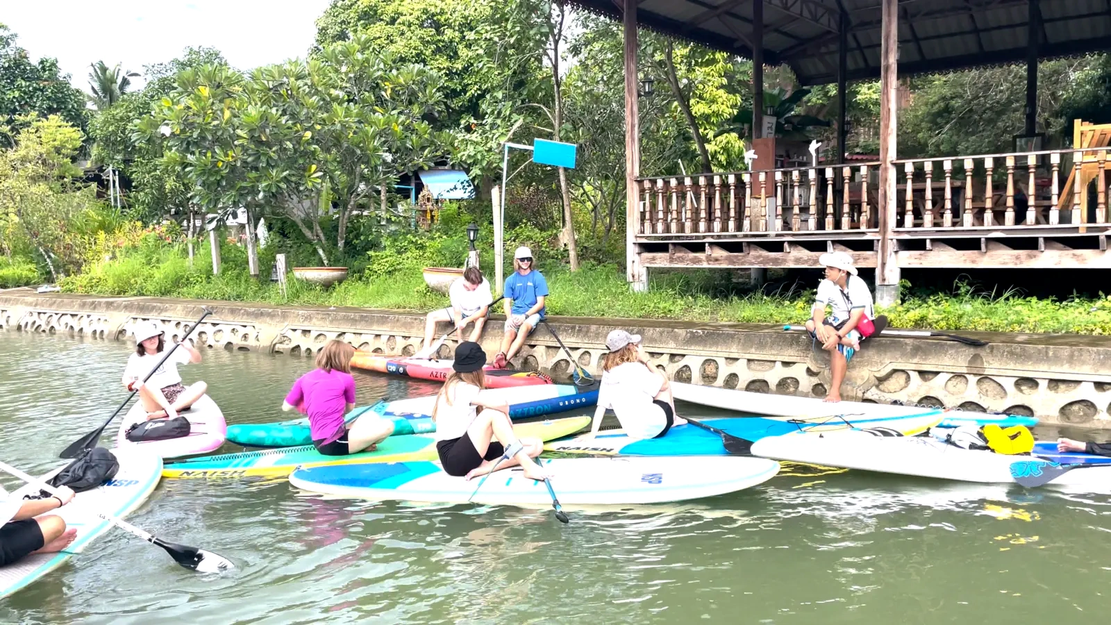 Students conducting fieldwork from paddleboards on a broad river
